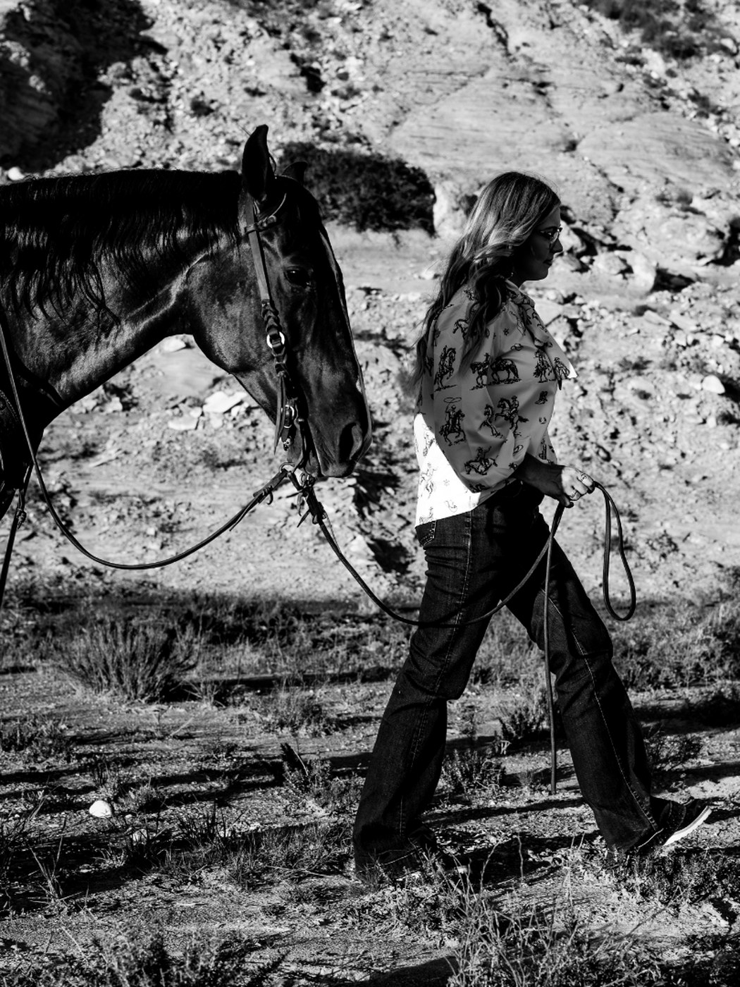 Madison leading her horse along a rocky draw